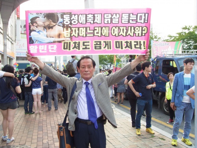 「同性愛祭りに鳥肌が立つ」などと書かれた横断幕を掲げる活貧団の洪貞植代表。反日を標榜する割に「日本から取材に来た」と言ったら嬉しそうにしていたのはナゼ……。（画像：筆者提供）