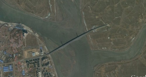 今年3月に撮影された新鴨緑江大橋の衛星写真。橋と中国側（左岸）の施設工事は完了しているが、北朝鮮側（右岸）の連絡道路の工事が全く行われていない。（画像：Google Earth）