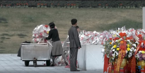 映画「アンダー・ザ・サン」の一場面。銅像に捧げられた花束が無造作に撤去されている（画像：Vitaly Mansky）