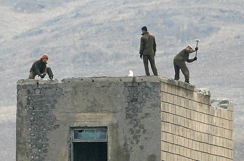 北朝鮮軍の38国境警備旅団朔州大隊の建物に登って工事を行う兵士たち。高さは10メートル以上もあるが、安全装備は一切身に着けていない。（画像：デイリーNK）